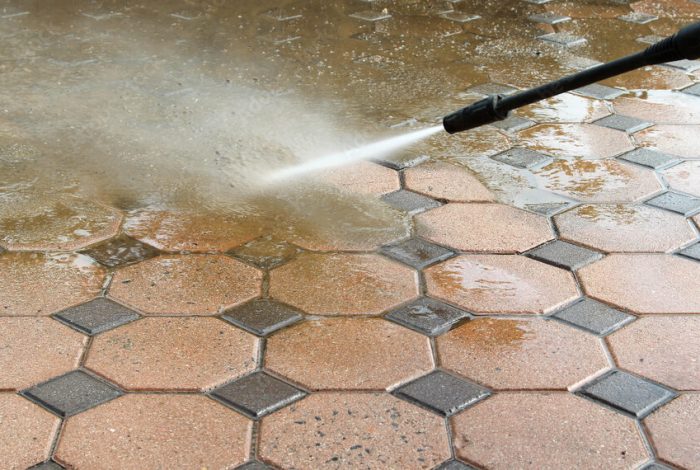 Cleaning concrete block floor by high pressure water jet.